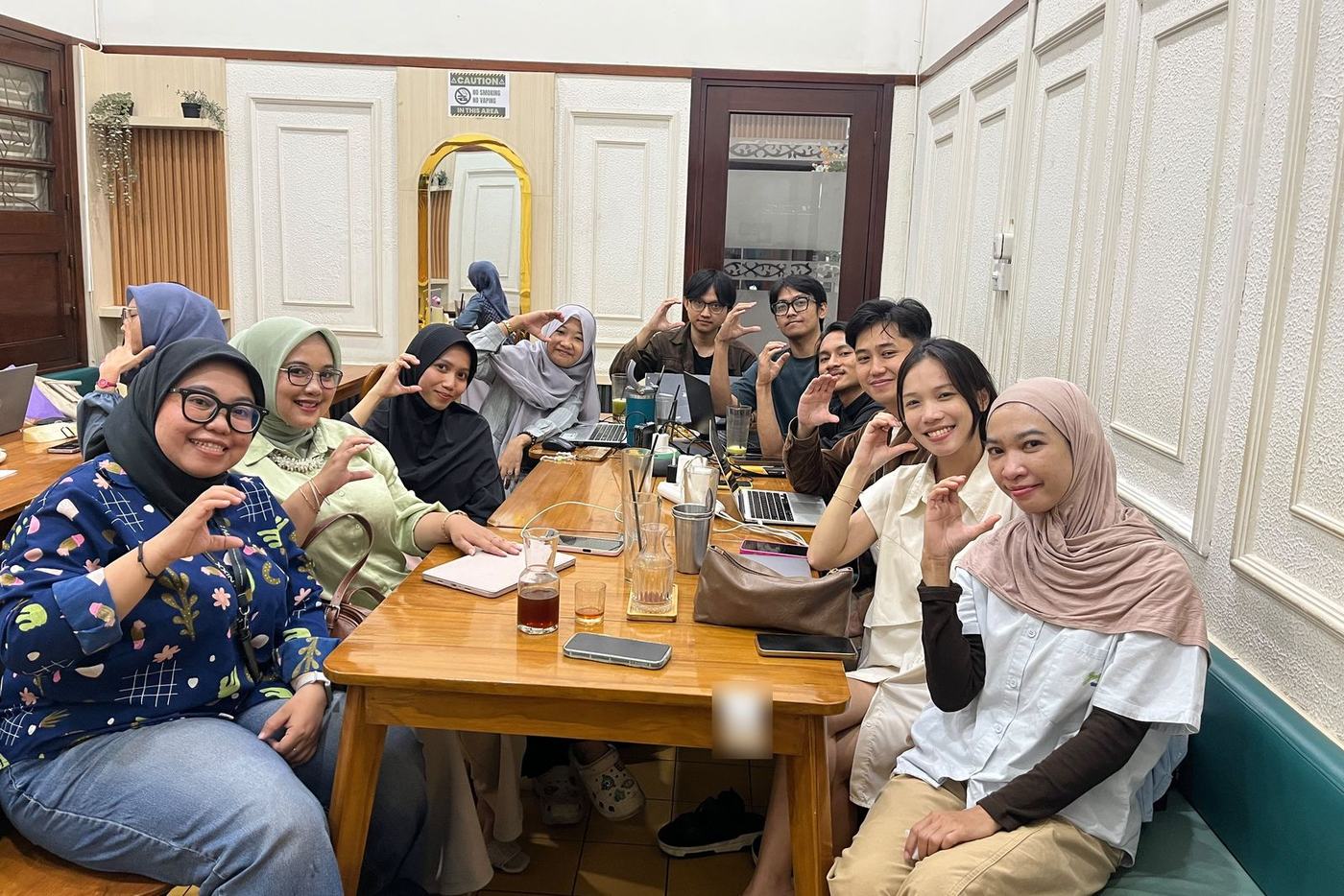 Peserta WFC berfoto bersama mengelilingi meja kayu di ruang kafe