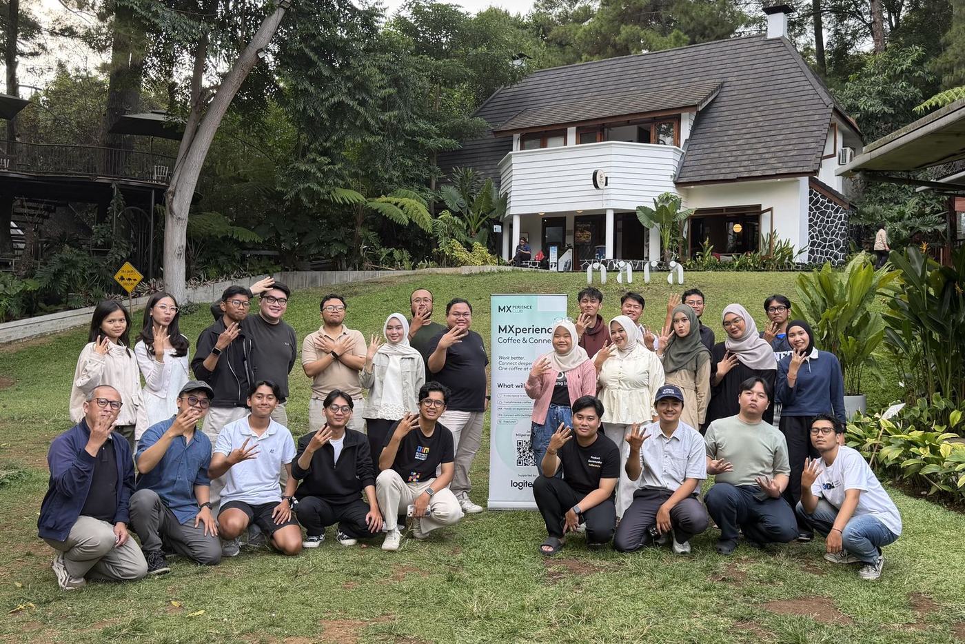 Peserta acara berfoto bersama di halaman rumput dengan banner MXperience